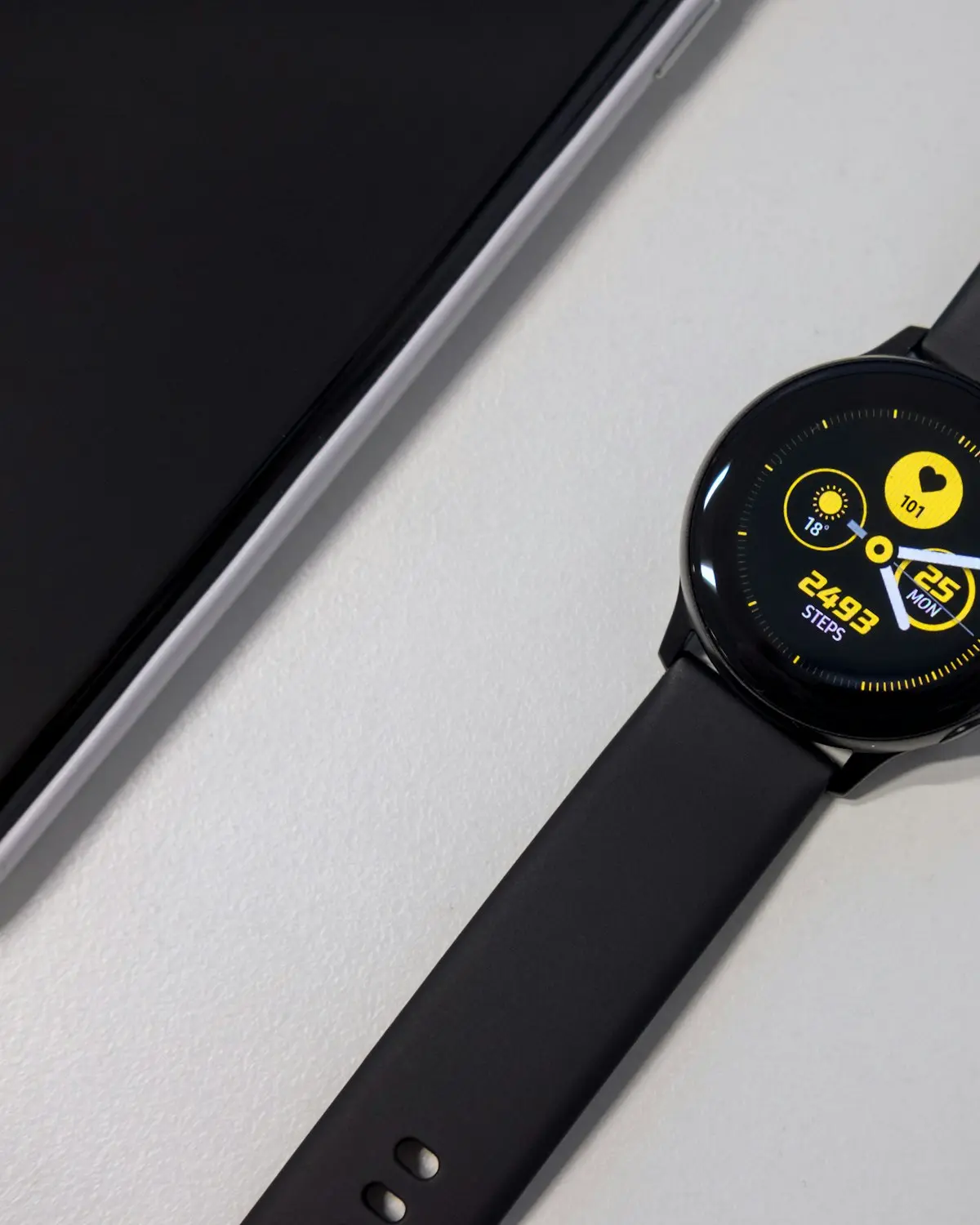 A wrist-worn device with a black strap, photographed on a plain surface.